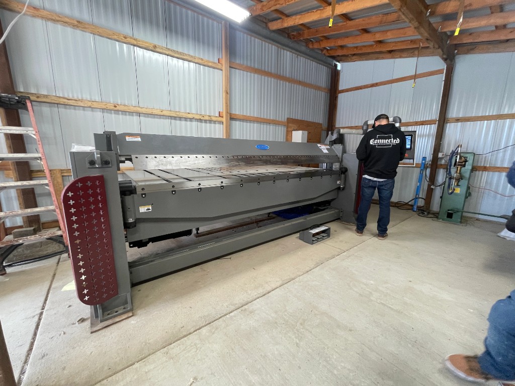 Technician operating a large industrial sheet metal folding machine in our custom metal fabrication workshop